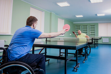 Adult disabled men in a wheelchair playing table tennis