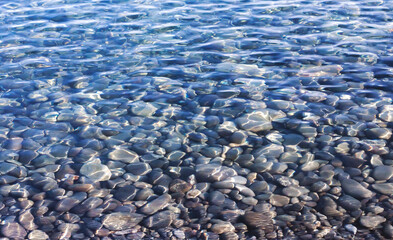The gray pebble bottom shines through the clear rippled water