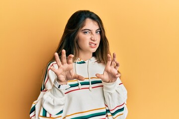 Young caucasian woman wearing casual clothes smiling funny doing claw gesture as cat, aggressive...