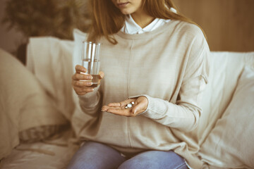 Fototapeta premium Close-up woman holding pills time to take medications, cure for headache, high blood pressure pain killer drugs at home. Stay at home concept during Coronavirus pandemic