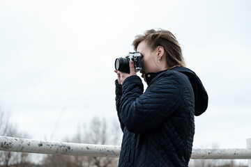Young woman taking pictures with a vintage film camera in riverside London.