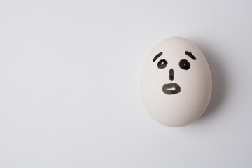 An egg with a surprised face, on a white background copy space.