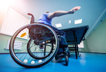 Disabled man in a wheelchair play at table tennis. Tennis balls fixed in a wheel