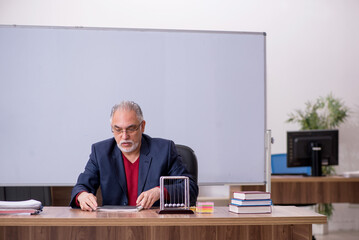 Old teacher physicist sitting in the classroom