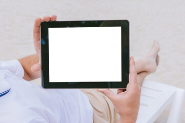 Mock up of a tablet in the hands of a blogger lying on a sun lounger on the beach. Against the background of sand. Travel concept.