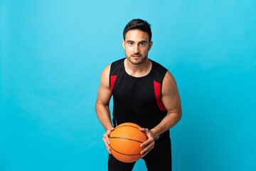 Young handsome man isolated on blue background playing basketball