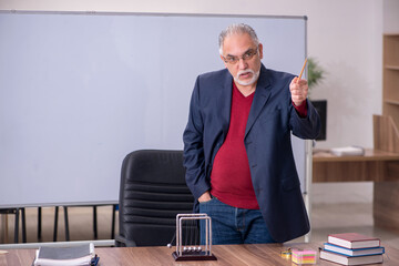 Old teacher physicist sitting in the classroom