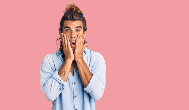 Young hispanic man wearing summer style afraid and shocked, surprise and amazed expression with hands on face