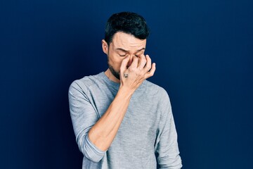 Young hispanic man wearing casual clothes tired rubbing nose and eyes feeling fatigue and headache. stress and frustration concept.