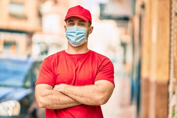 Fototapeta na wymiar Young caucasian deliveryman wearing medical mask standing at the city.