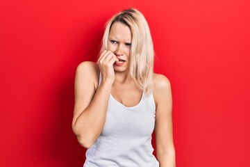 Fototapeta premium Beautiful caucasian blonde woman wearing casual white t shirt looking stressed and nervous with hands on mouth biting nails. anxiety problem.