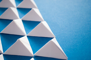 Close up of white paper triangles on blue background