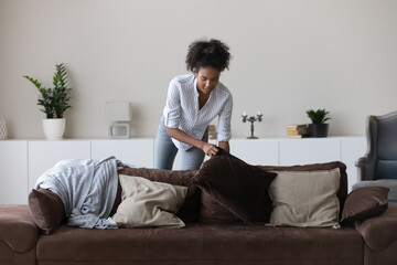 Young African American woman clean cozy new modern apartment or house on weekend day. Millennial...