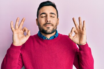 Young hispanic man wearing casual clothes relaxed and smiling with eyes closed doing meditation gesture with fingers. yoga concept.