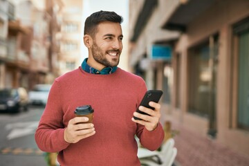 Young hispanic man using smartphone and drinking coffee at the city.