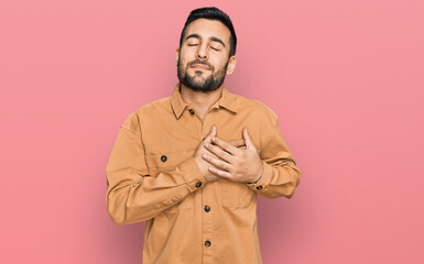 Young hispanic man wearing casual clothes smiling with hands on chest with closed eyes and grateful gesture on face. health concept.