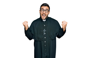 Young hispanic man wearing priest uniform screaming proud, celebrating victory and success very...