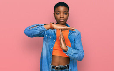Young african american woman wearing casual clothes doing time out gesture with hands, frustrated...