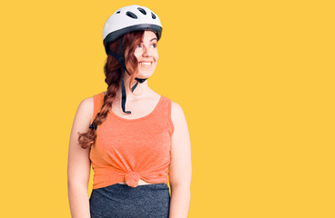Young beautiful woman wearing bike helmet looking away to side with smile on face, natural expression. laughing confident.
