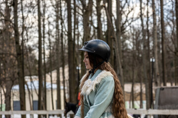 beautiful girl in a blue outfit and a light brown horse in a spring forest