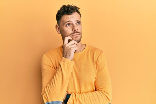 Young hispanic man wearing casual clothes thinking concentrated about doubt with finger on chin and looking up wondering