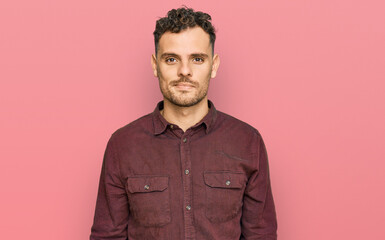 Young hispanic man wearing casual clothes relaxed with serious expression on face. simple and natural looking at the camera.