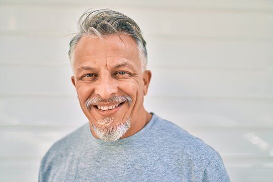 Middle age hispanic grey-haired man smiling happy standing at the city.