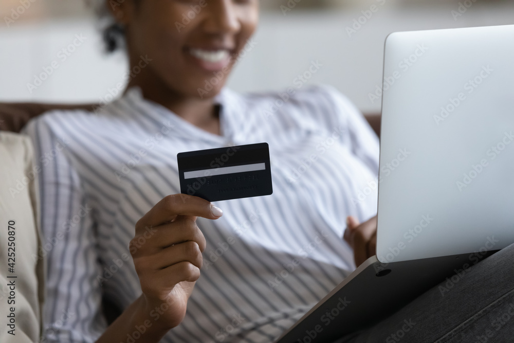 Wall mural crop close up of happy african american woman make internet payment with credit card on laptop. smil