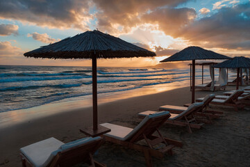 Scenic sunrise on the beach, silhouettes of beach umbrellas. Greece, Crete. 