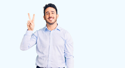 Young hispanic man wearing business clothes showing and pointing up with fingers number two while smiling confident and happy.