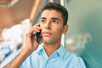 Young latin man with serious expression talking on the smartphone at the city.