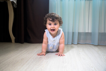 Baby Girl In Summer Dress Sit on wooden floor inside room.