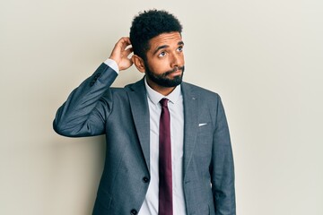 Handsome hispanic man with beard wearing business suit and tie confuse and wondering about...