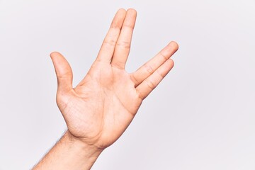 Close up of hand of young caucasian man over isolated background greeting doing vulcan salute, showing hand palm and fingers, freak culture