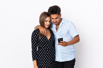 Young caucasian couple isolated on white background sending a message or email with the mobile