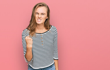 Obraz premium Beautiful blonde woman wearing casual clothes angry and mad raising fist frustrated and furious while shouting with anger. rage and aggressive concept.