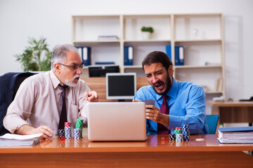 Two male employees playing cards at workplace