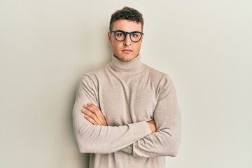 Hispanic young man wearing casual turtleneck sweater skeptic and nervous, disapproving expression on face with crossed arms. negative person.