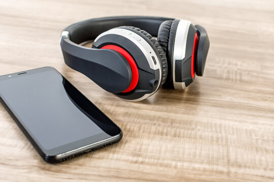 Cell Phone And Wireless Headphones On Wooden Table.