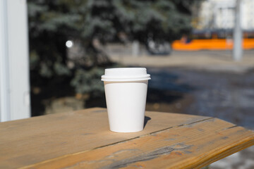 Disposable cup of coffee standing on table outside in the city.