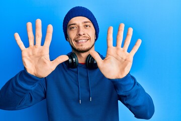 Naklejka premium Hispanic young man wearing sweatshirt and headphones showing and pointing up with fingers number ten while smiling confident and happy.