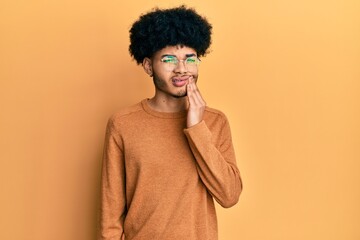 Fototapeta na wymiar Young african american man with afro hair wearing casual winter sweater touching mouth with hand with painful expression because of toothache or dental illness on teeth. dentist