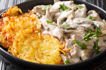 Swiss Zurich veal with mushrooms in a creamy sauce with potato pancakes close-up in a plate. horizontal