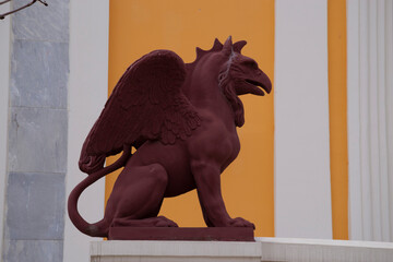 The figure of a griffin on the background of a yellow-and-white wall.