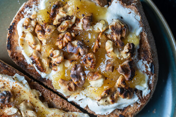 Two bread toast with cream cheese, roasted walnuts, honey, pepper and salt, close up, top view
