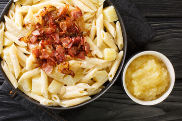 Tasty Alpine macaroni alplermagronen is pasta, cheese with potatoes, onion and bacon closeup in the...