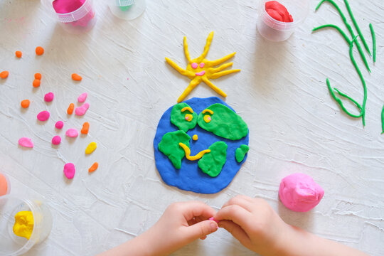 Child sculpturing plasticine planet for earth day. Protection of environment, Save our planet. Ecology concept. Concept of art learning and education, love earth , save world and unity.
