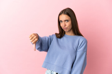 Young woman over isolated pink background showing thumb down with negative expression