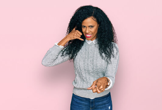 Middle age african american woman wearing casual clothes smiling doing talking on the telephone gesture and pointing to you. call me.