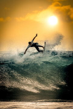 Young surfer with with wetsuit enjoying big waves in Tenerife, Canary Islands. Sporty boy riding his surf board on the ocean wave. Brave teenager making tricks on the rough sea during a competition.
